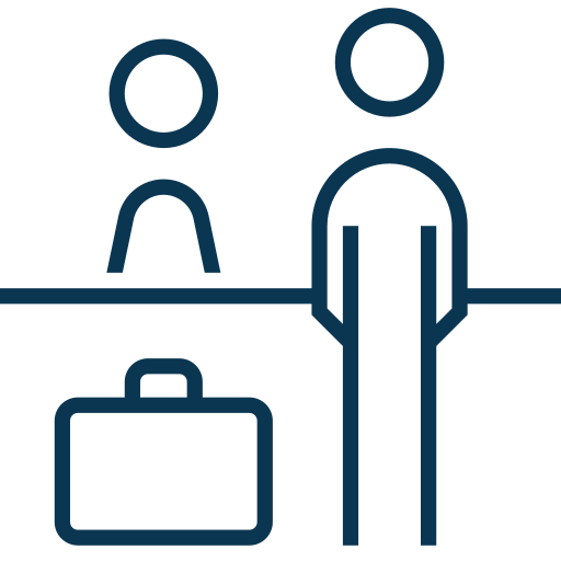 Simple line drawing of two people, one standing behind a counter and the other in front of it with a suitcase nearby, suggesting a reception or check-in desk.